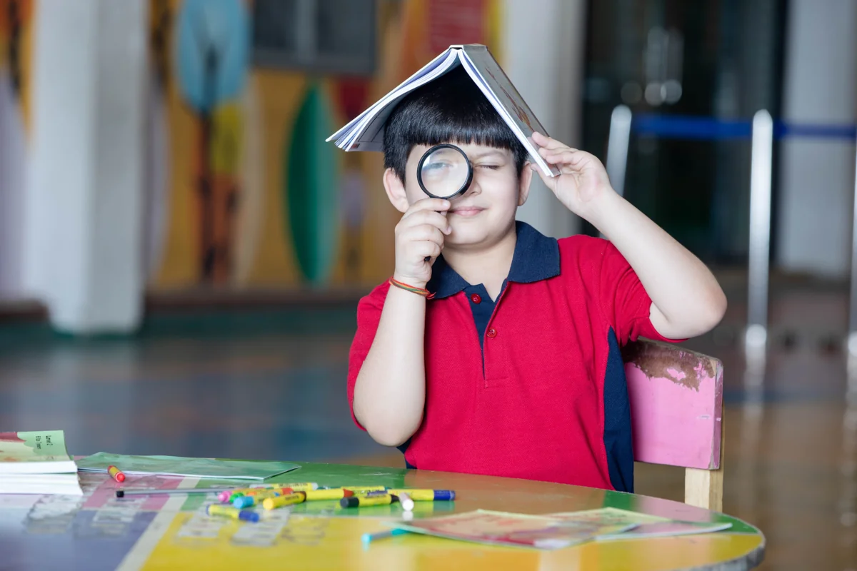 Child exploring with a magnifying glass at a colourful learning desk